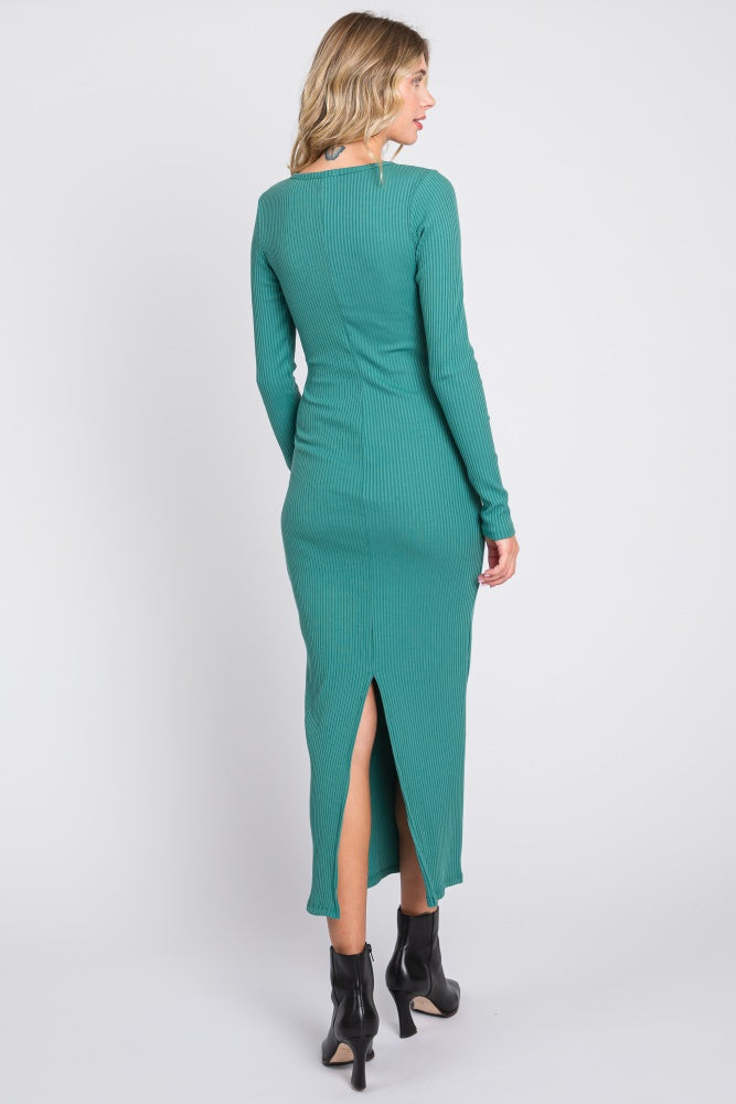 woman wearing a green ribbed knit long sleeve dress with a side slit and high neckline, viewed from the back