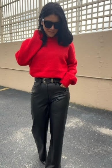 woman wearing a red oversized sweater and black faux leather wide-leg pants, accessorized with sunglasses