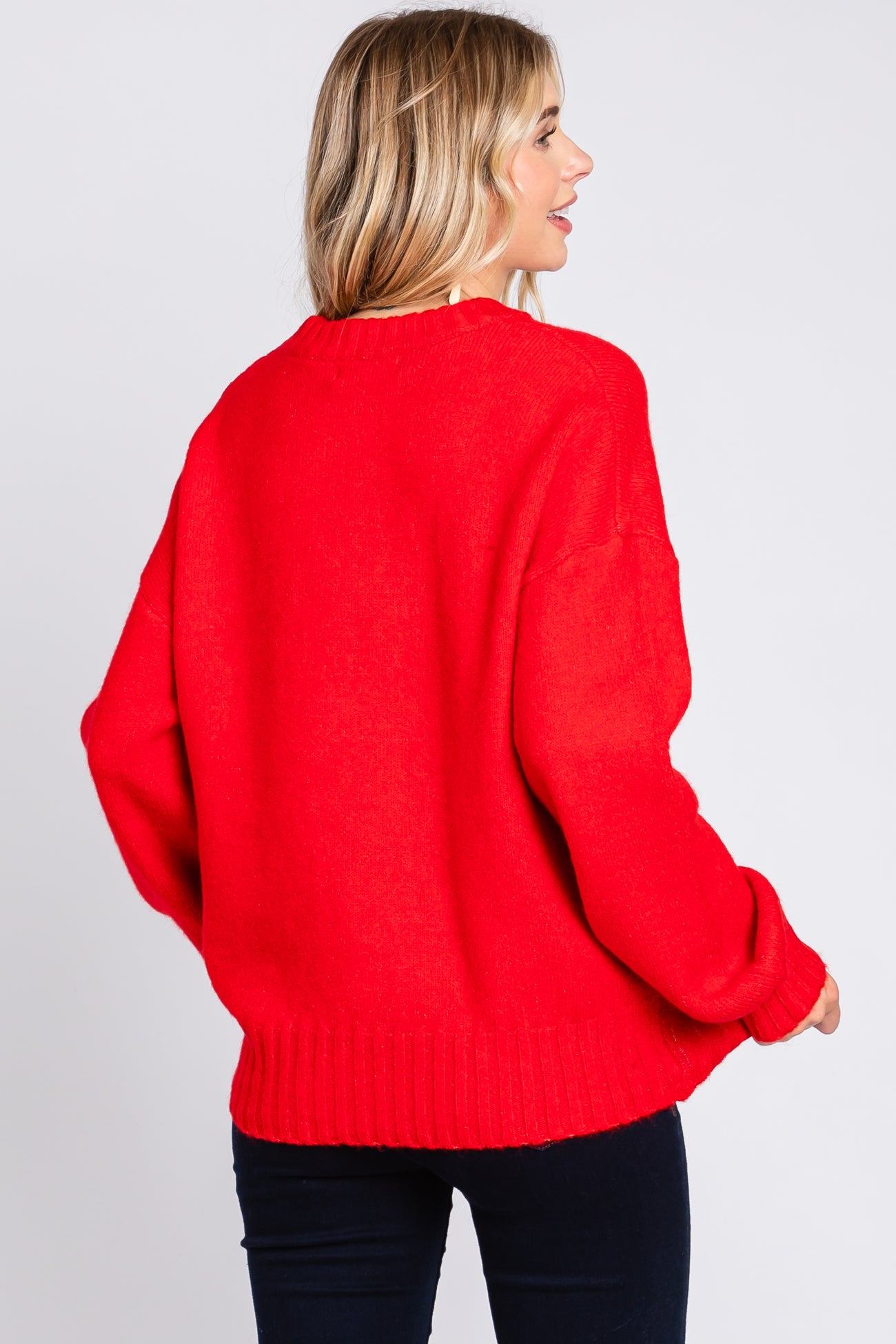 woman wearing a bright red oversized sweater with ribbed hem and loose fit, facing away from the camera