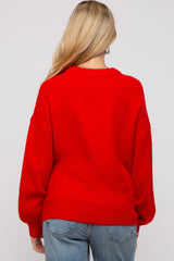 woman wearing a bright red oversized maternity sweater with a relaxed fit, styled with denim jeans