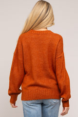 woman wearing an orange maternity sweater with a loose fit and long sleeves, viewed from the back