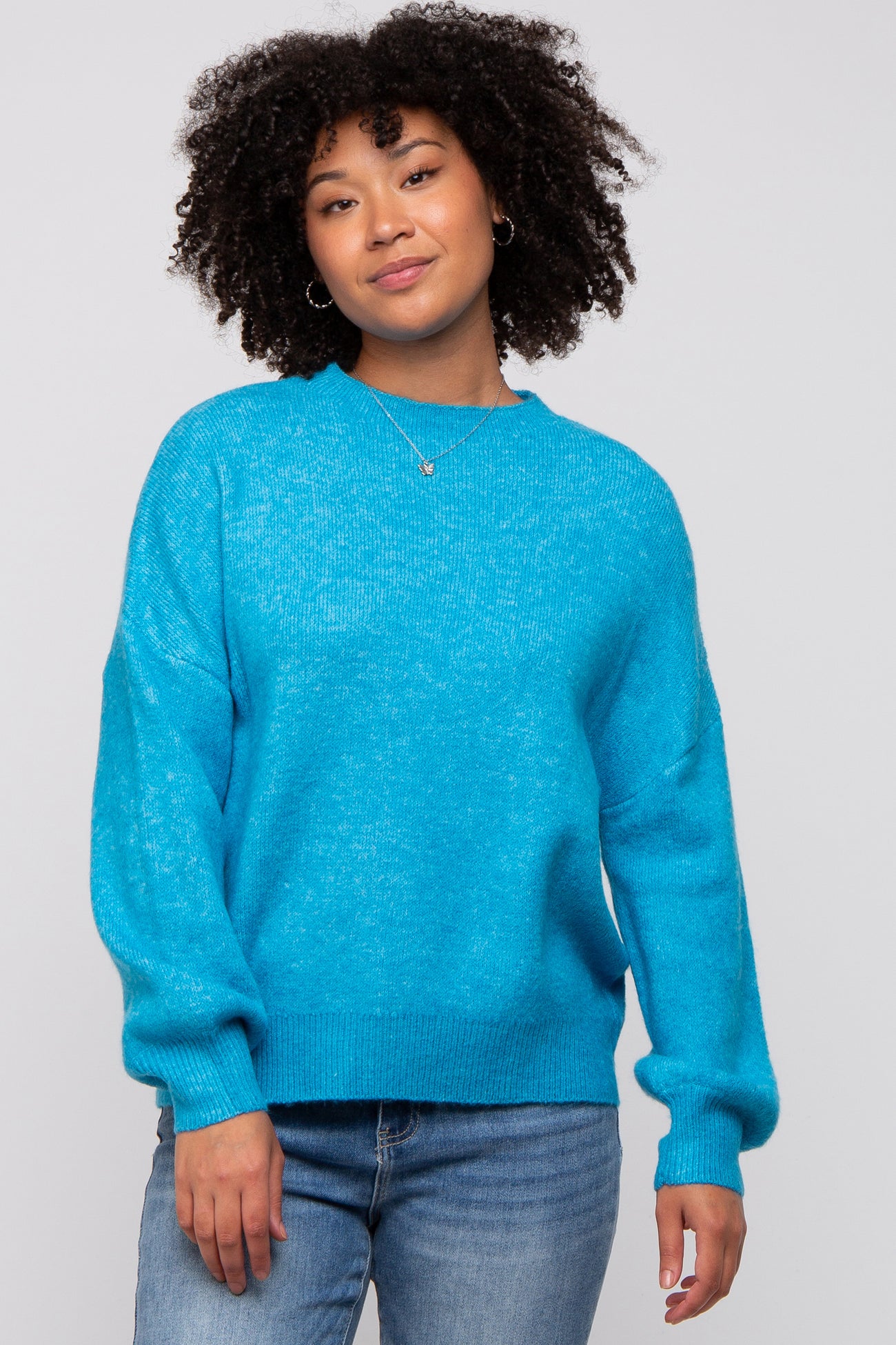 woman wearing a bright blue oversized sweater with long sleeves and a relaxed fit, paired with denim jeans