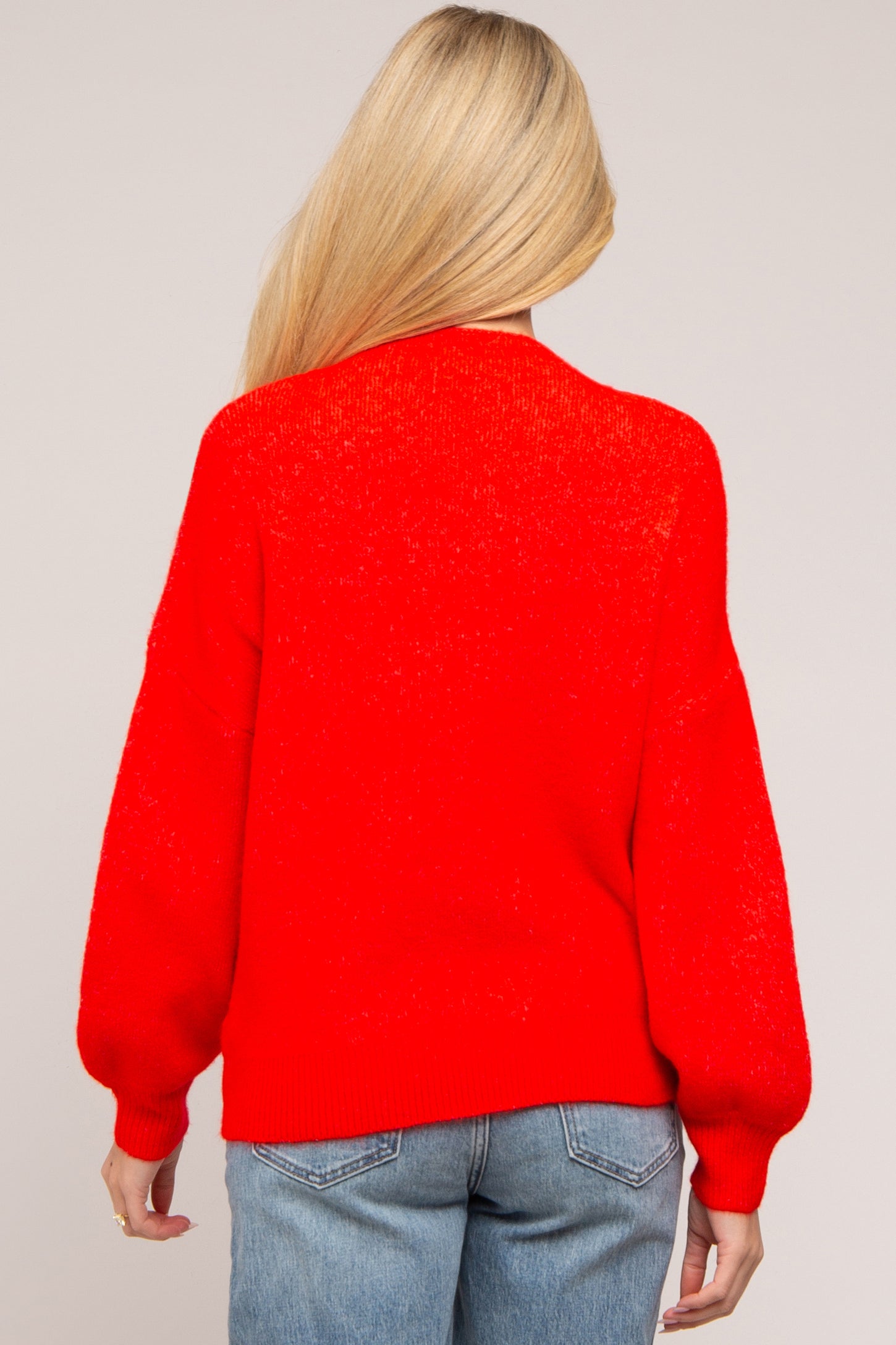 woman wearing a bright red oversized maternity sweater with balloon sleeves, viewed from the back