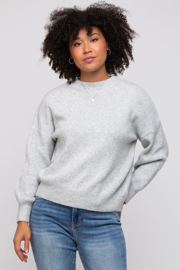 woman wearing a light gray oversized sweater with balloon sleeves paired with blue jeans