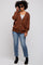 woman wearing a brown oversized cardigan with buttons, styled with a light gray top and blue jeans, accessorized with sunglasses