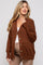 woman wearing a warm brown maternity cardigan with a relaxed fit and button details, styled over a white top