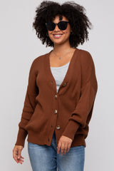 woman wearing a brown button-up cardigan with a v-neckline and a relaxed fit, paired with a gray top and blue jeans