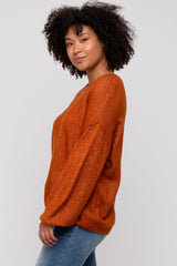 woman wearing an orange oversized sweater with long sleeves and a relaxed fit, paired with blue jeans