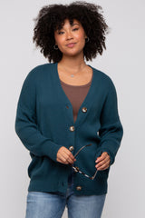 woman wearing a teal button-up cardigan over a brown top and holding sunglasses