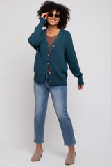 woman wearing a teal button-up cardigan over a gray top and blue jeans, smiling and wearing sunglasses