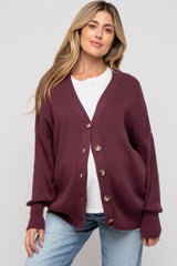 woman wearing a maroon maternity cardigan over a white top and light blue jeans