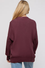 woman wearing a burgundy oversized maternity sweater, viewed from the back