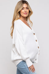 woman wearing a white oversized knit maternity cardigan with button details and a visible baby bump