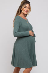 woman wearing a green ribbed maternity dress with long sleeves and a tie waist, highlighting her baby bump