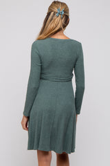 woman wearing a green long sleeve maternity dress with a fitted bodice and flared skirt from the back