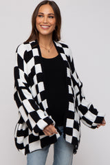woman wearing a black and white checkered maternity cardigan over a black top and showing her baby bump