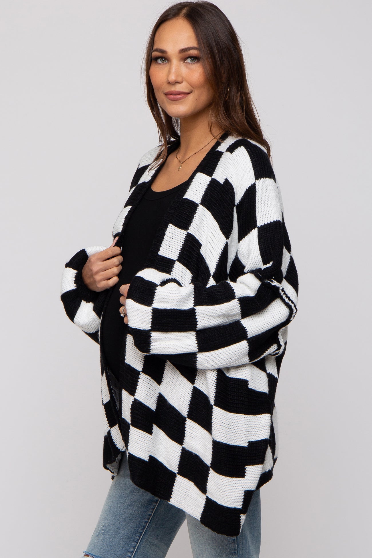 woman wearing a black and white checkered maternity cardigan and showing her baby bump