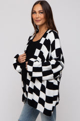 woman wearing a black and white checkered maternity cardigan and showing her baby bump