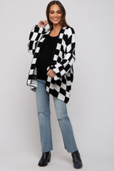 woman wearing a black and white checkered maternity cardigan over a black top and distressed jeans