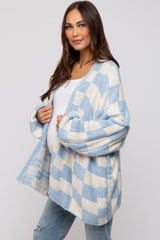 woman wearing a blue and white checkered maternity cardigan and showing her baby bump