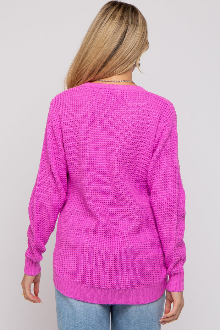 woman wearing a bright pink long sleeve knitted maternity sweater, shown from the back