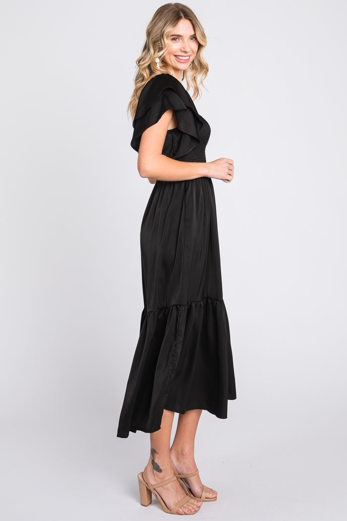 woman wearing a black off-the-shoulder maxi dress with ruffle details and a tiered skirt