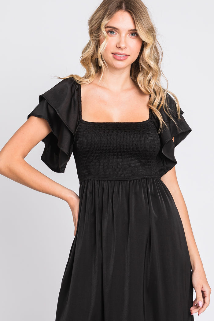woman wearing a black smocked off-the-shoulder dress with ruffle sleeves
