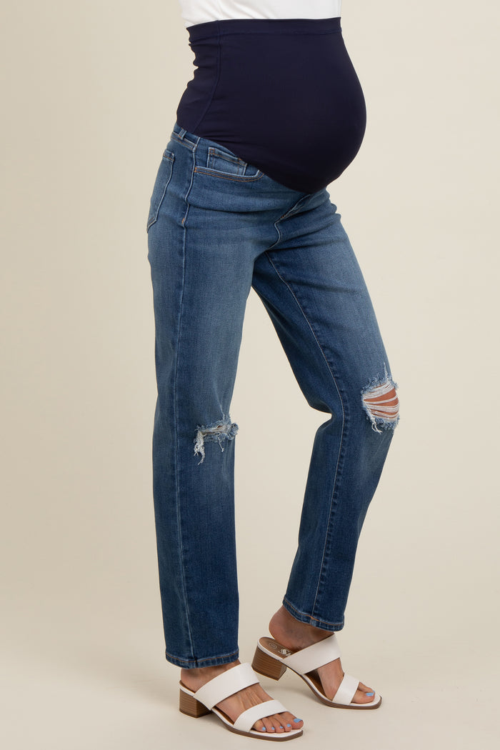 woman wearing dark blue maternity jeans with a ribbed belly band, showing her baby bump, styled with white heeled sandals
