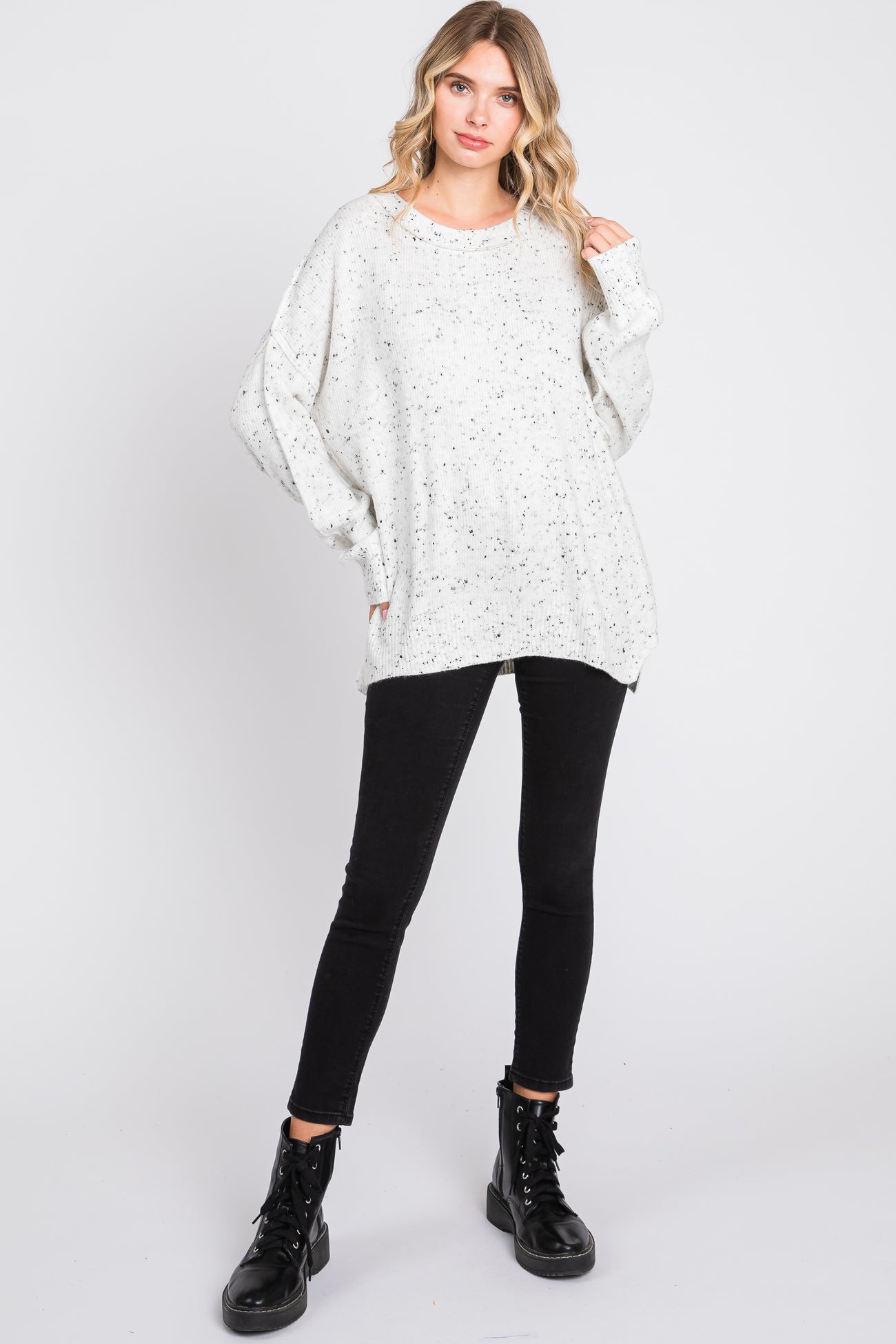woman wearing a white speckled oversized sweater and black skinny jeans with black combat boots
