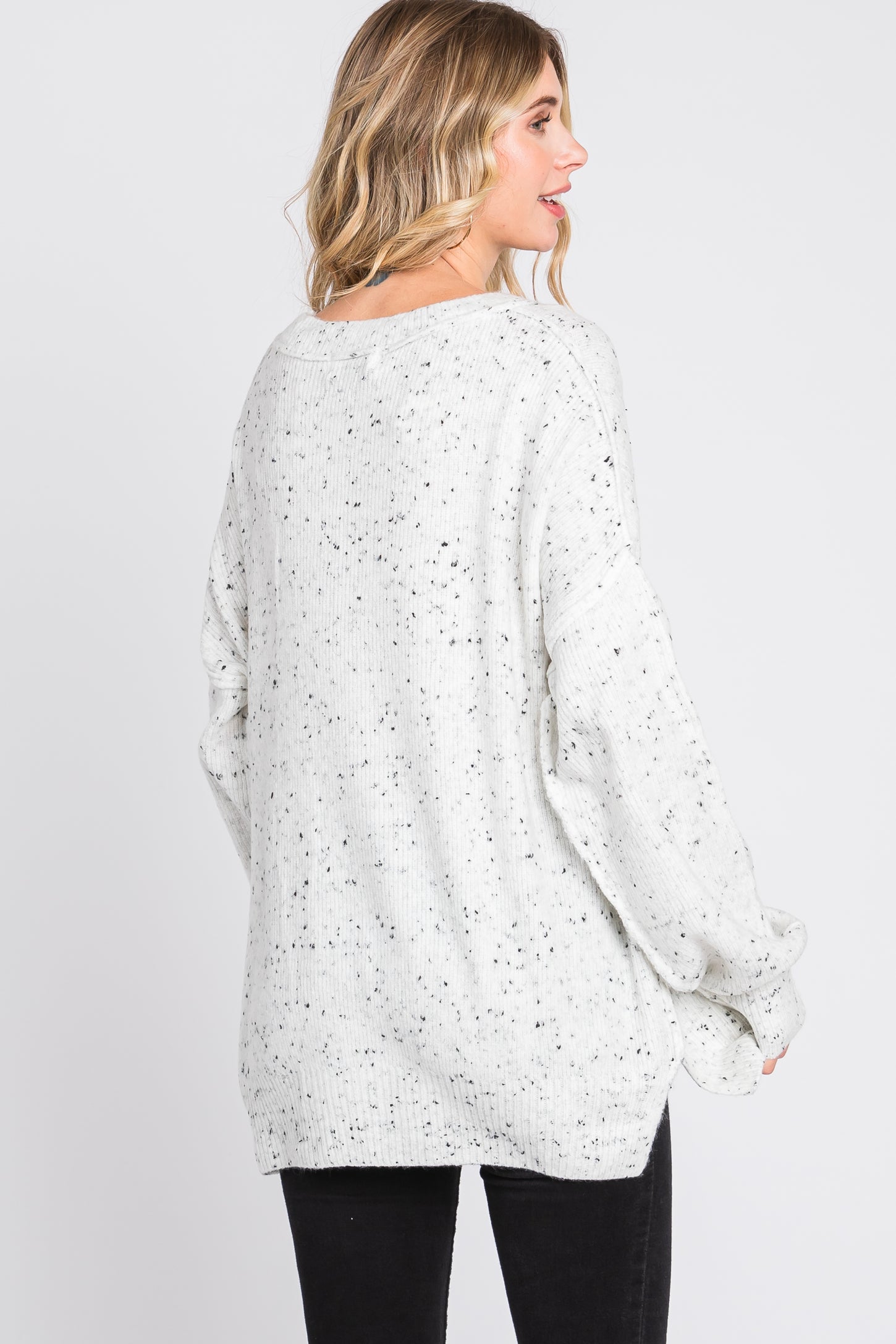 woman wearing a light gray speckled oversized sweater with a relaxed fit and long sleeves