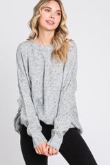 woman wearing a light gray oversized knitted sweater with a relaxed fit and speckled detailing, paired with black jeans