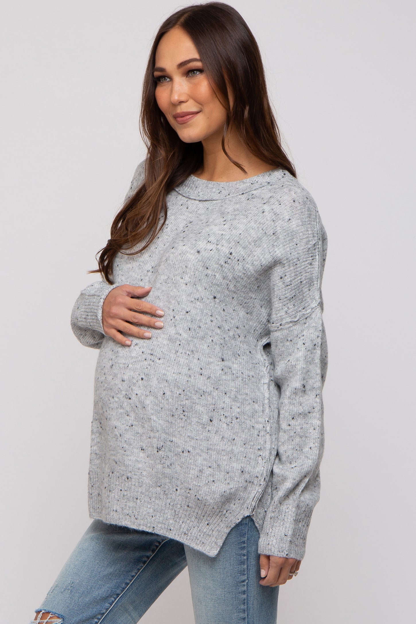 woman wearing a gray speckled maternity sweater and holding her baby bump