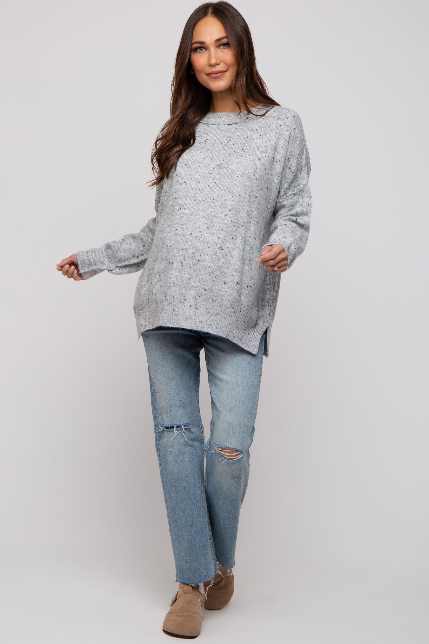 woman wearing a gray oversized maternity sweater with a loose fit and distressed jeans, featuring a relaxed style