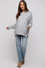 woman wearing a gray oversized maternity sweater with a loose fit and distressed jeans, featuring a relaxed style