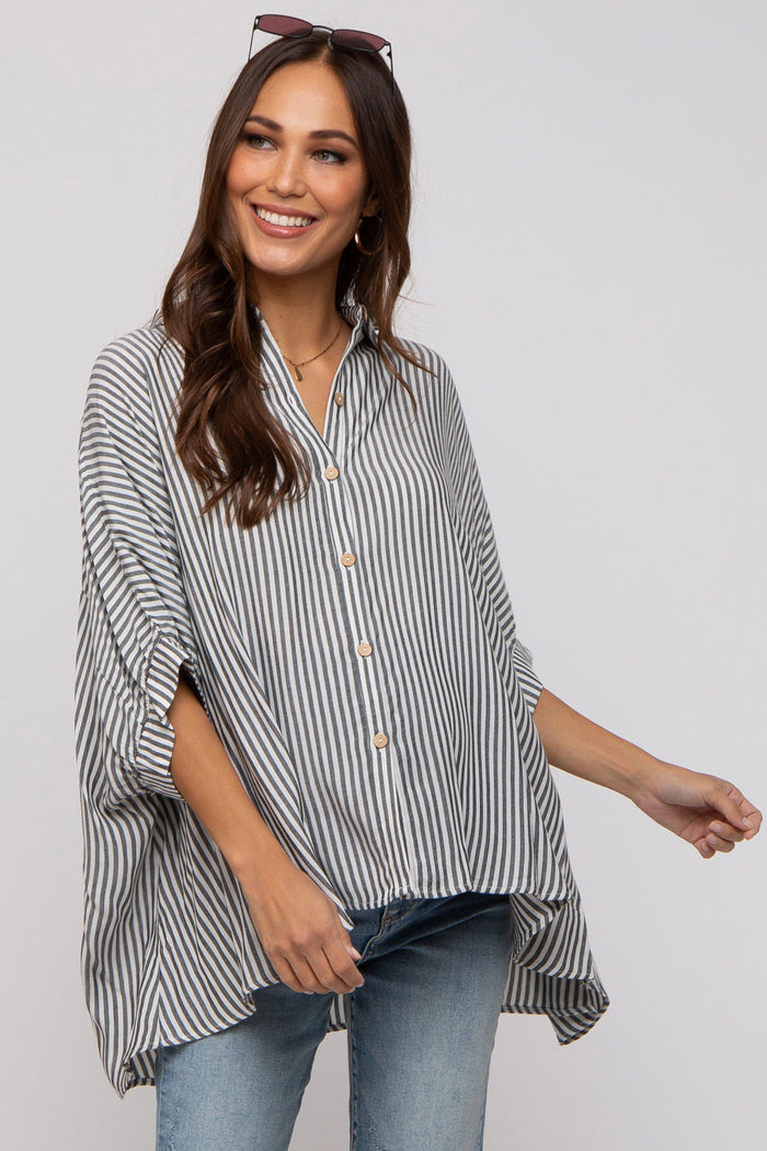 woman wearing a striped maternity top with a button-down front and relaxed fit, smiling while standing against a light background