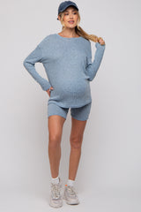 woman wearing a light blue ribbed maternity set with long sleeves and shorts, showing her baby bump and styled with a cap