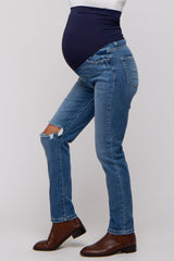 woman wearing blue distressed maternity jeans with a dark blue belly support band and showcasing a baby bump
