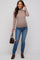 woman wearing a tan ribbed maternity top and blue distressed jeans, showing her baby bump and holding a brown handbag