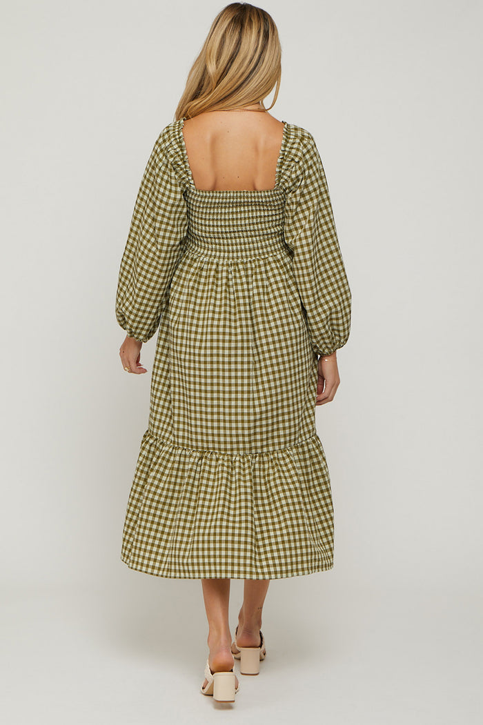woman wearing a green and white gingham maternity dress with puffed sleeves and a tiered hem, showing a baby bump