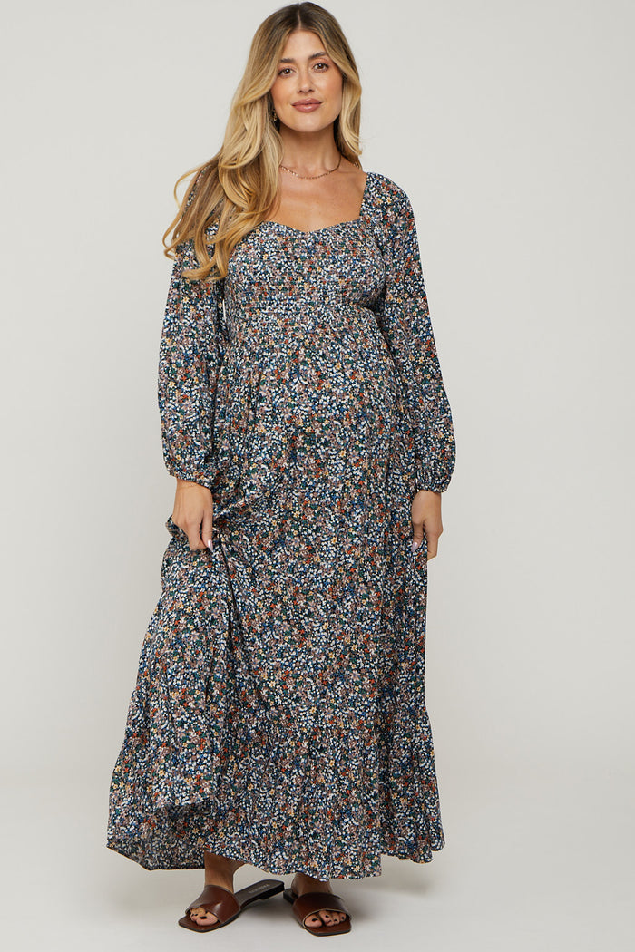 woman wearing a floral long sleeve maternity dress with a square neckline and a flowing skirt, highlighting her baby bump
