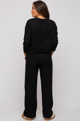 woman wearing a black ribbed long sleeve maternity top and matching pants, showing the back view