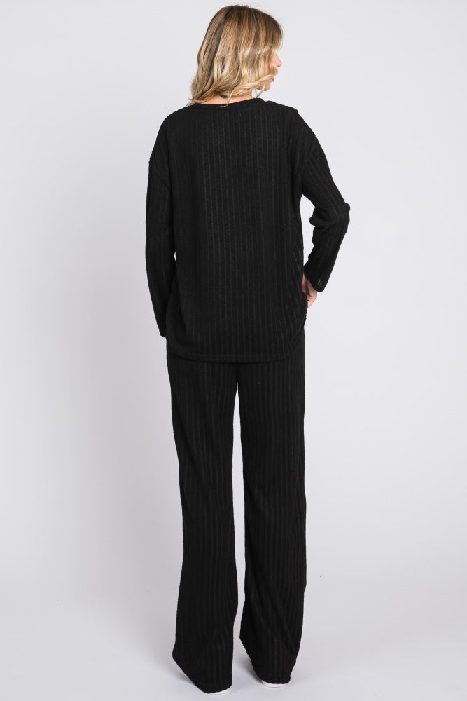 woman wearing a black ribbed lounge set consisting of a long sleeve top and wide-leg pants, viewed from the back