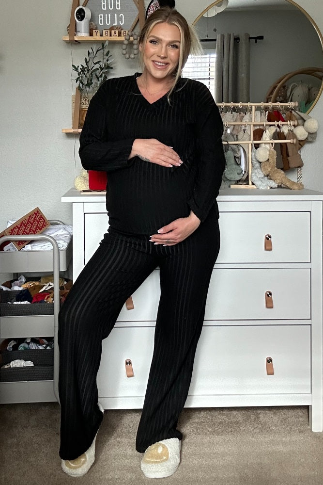 woman wearing a black striped maternity pajama set and cradling her baby bump