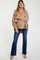 woman wearing a light brown maternity top with balloon sleeves and dark blue flared jeans