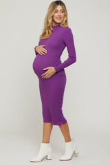 woman wearing a purple long sleeve maternity dress with button details and holding her baby bump