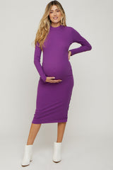 woman wearing a purple long sleeve maternity dress and holding her baby bump