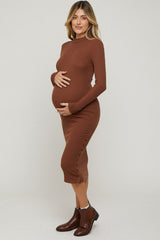 woman wearing a brown long sleeve maternity dress with button details and holding her baby bump
