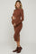 woman wearing a brown long sleeve maternity dress with button details and holding her baby bump
