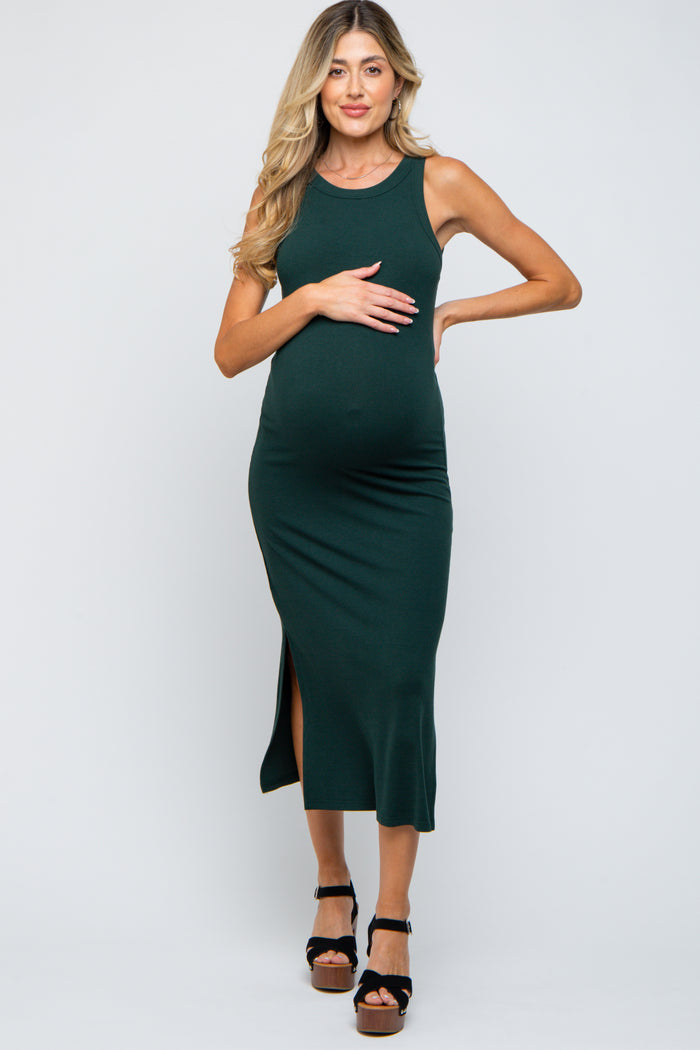woman wearing a dark green ribbed maternity dress with a side slit and holding her baby bump