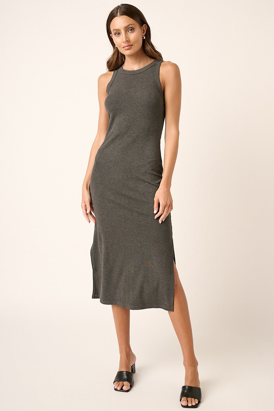 woman wearing a fitted dark gray sleeveless midi dress with side slits and a scoop neckline